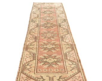 May include: A long, rectangular rug with a pink and beige color scheme. The rug features a traditional Turkish design with intricate floral and geometric patterns.