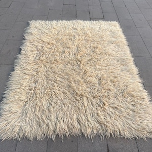 Könnte beinhalten: Ein flauschiger weißer Shaggy-Teppich mit langem Flor. Der Teppich besteht aus weichen, plüschigen Fasern und hat ein natürliches, organisches Aussehen.
