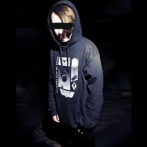 May include: Black hooded sweatshirt with a white graphic print that says "ILLUSIONS KEEP ME GOING". The graphic is a collage of black and white images.