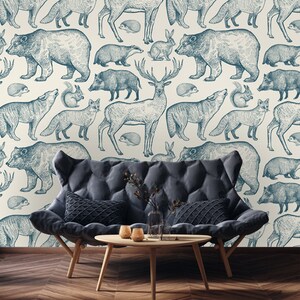 Puede incluir: Un fondo blanco con un patr&oacute;n repetitivo de ilustraciones azules y blancas de varios animales del bosque, incluyendo ciervos, osos, zorros, ardillas y conejos. Un sof&aacute; azul oscuro con un marco de madera y dos almohadas se encuentra frente al fondo estampado.