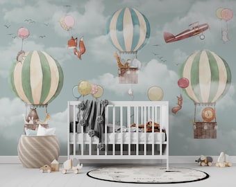 May include: A nursery room with a light blue wall featuring a whimsical mural of hot air balloons with animal passengers. The balloons are green, white, and blue with yellow, pink, and red accents. A white crib with a gray blanket is in the foreground.