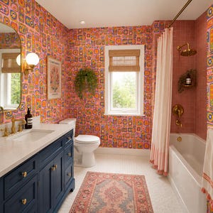 May include: A colorful bathroom with a vibrant floral wallpaper in shades of pink, orange, and blue. Features a navy blue vanity with a white countertop, a white bathtub, and a patterned rug. Gold fixtures and a window with a bamboo shade complete the design.