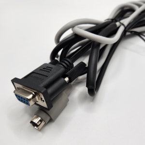 May include: A black and gray cable with a 9-pin serial connector and a smaller connector on the other end.