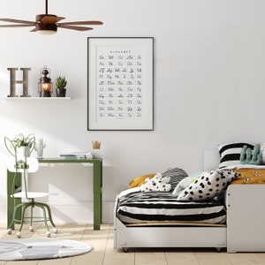 May include: A white daybed with black and white striped bedding and a black and white polka dot pillow. There is a yellow pillow with white stars on it. A green desk with a white chair is in the background. A framed alphabet chart hangs on the wall.