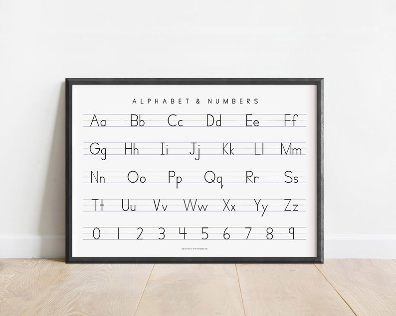 May include: Black and white alphabet and number chart with the letters A through Z and the numbers 0 through 9. The chart is framed in a black frame and is hanging on a white wall.