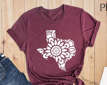 May include: A heather maroon t-shirt with a white outline of the state of Texas, filled with a mandala design. The text "PEGASUS ApparelUS" is in the top right corner of the image.