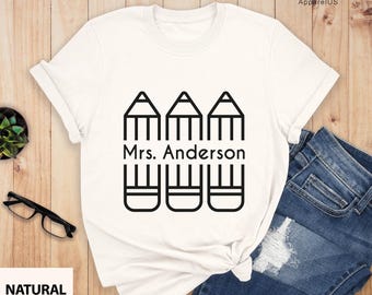 May include: White t-shirt with a black graphic of three pencils and the text "Mrs. Anderson".