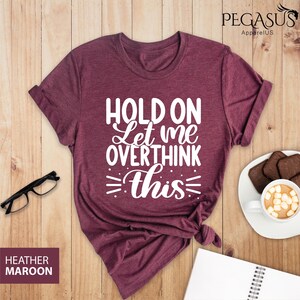 May include: A heather maroon t-shirt with the text "HOLD ON Let me OVERTHINK this" printed in white.