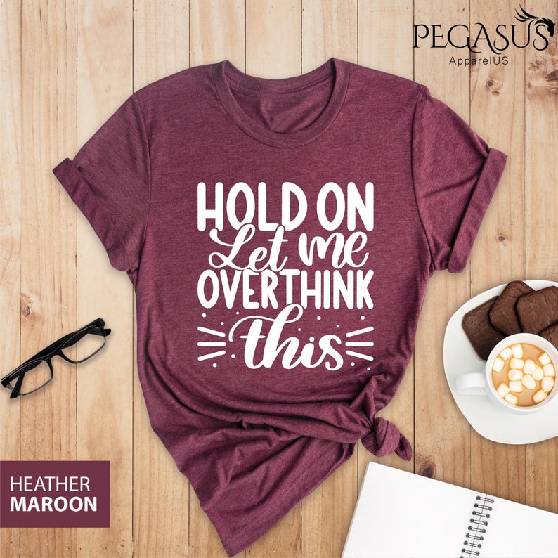 May include: A heather maroon t-shirt with the text "HOLD ON Let me OVERTHINK this" printed in white.
