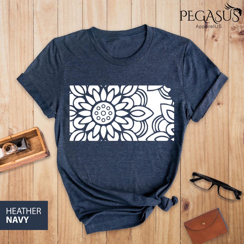 May include: A heather navy blue t-shirt with a white mandala design in the shape of the state of Kansas.