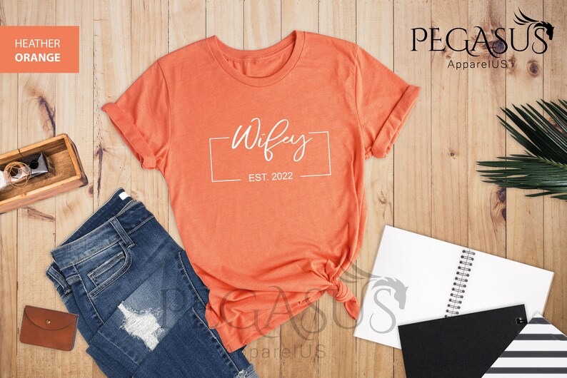 May include: A heather orange t-shirt with the text "Wifey Est. 2022" in a white box.