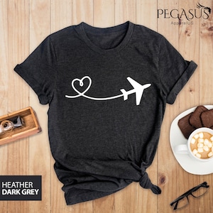 Puede incluir: Camiseta gris oscuro jaspeada con un avi&oacute;n y un coraz&oacute;n blancos. El avi&oacute;n est&aacute; volando lejos de un coraz&oacute;n.
