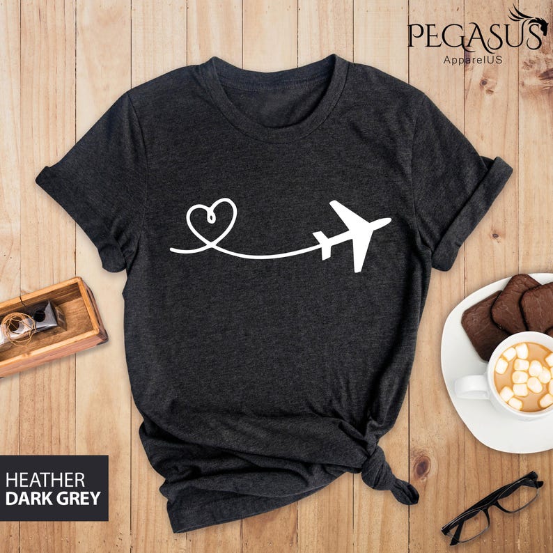 Puede incluir: Camiseta gris oscuro jaspeada con un avi&oacute;n y un coraz&oacute;n blancos. El avi&oacute;n est&aacute; volando lejos de un coraz&oacute;n.