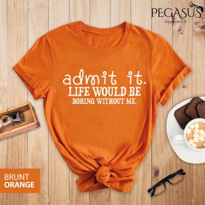 May include: Orange t-shirt with the text "admit it. LIFE WOULD BE BORING WITHOUT ME." printed in white.
