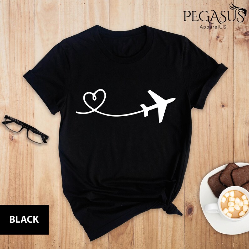Puede incluir: Camiseta negra con un avi&oacute;n y un coraz&oacute;n blancos. El avi&oacute;n est&aacute; volando lejos de un coraz&oacute;n.