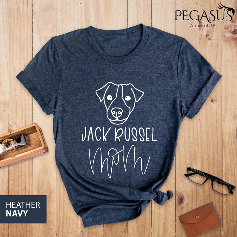 May include: Heather navy blue t-shirt with a white graphic of a Jack Russell Terrier dog and the words "Jack Russel Mom". The shirt is made of a soft material and is perfect for dog lovers.