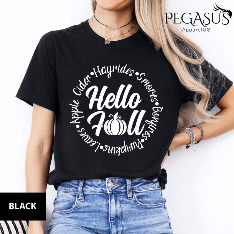 May include: Black t-shirt with a white circular design that says "Hello Fall" with a pumpkin graphic. The design also includes the words "Cider, Hayrides, S'mores, Bonfires, Pumpkins, Leaves, and Apple."