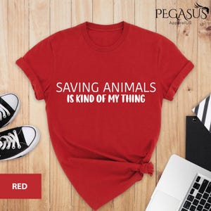 May include: Red t-shirt with the text "Saving Animals is Kind of My Thing" in white lettering.