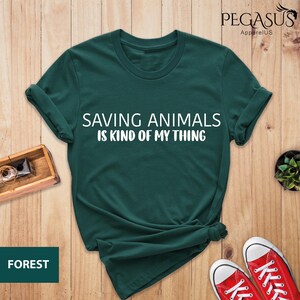 May include: A dark green t-shirt with the text "Saving Animals is Kind of My Thing" in white lettering.