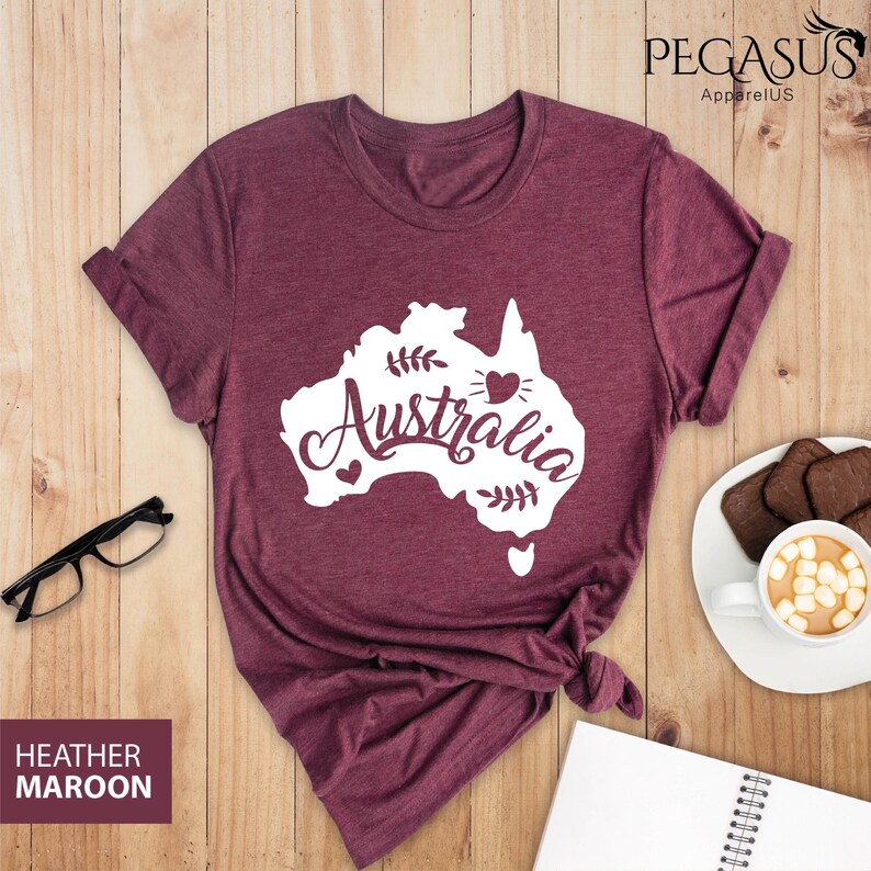 Op de afbeelding: Heather-marronkleurig T-shirt met een witte omtrek van het continent Australi&euml; en het woord "Australi&euml;" in een wit cursief lettertype. De omtrek bevat een klein hartje in het midden van het continent en kleine hartjes aan weerszijden van het woord "Australi&euml;".