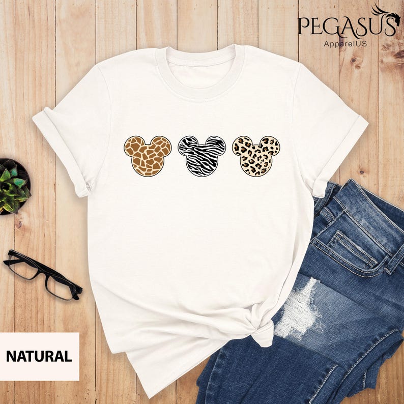 May include: White t-shirt with three Mickey Mouse heads in a row. Each head is a different animal print: giraffe, zebra, and leopard.