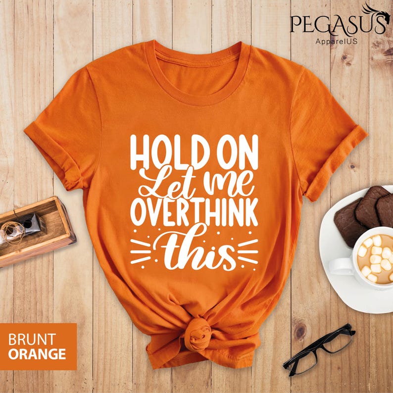 May include: Orange t-shirt with the text "Hold on Let me overthink this" in white lettering.
