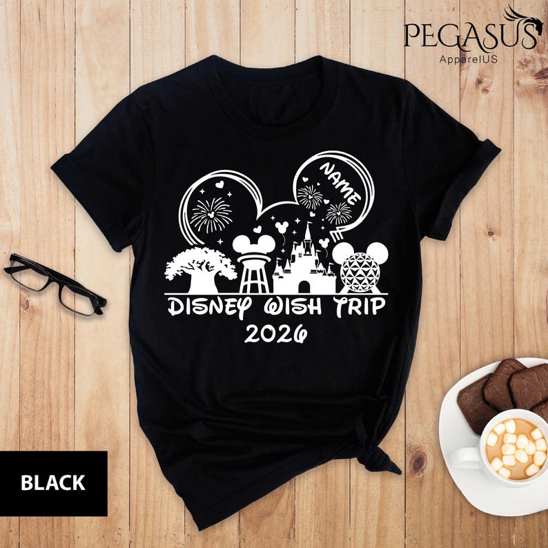 May include: Black t-shirt with a white graphic featuring Mickey Mouse ears, fireworks, a castle, and the text "Disney Wish Trip 2026". The word "NAME" is inside one of the ears. The word "BLACK" is at the bottom left.