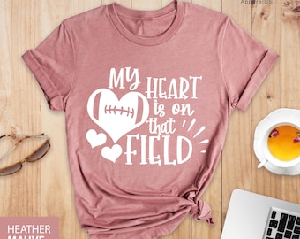 May include: A heather mauve t-shirt with the text "My heart is on that field!" in white. A white football is inside a heart shape.