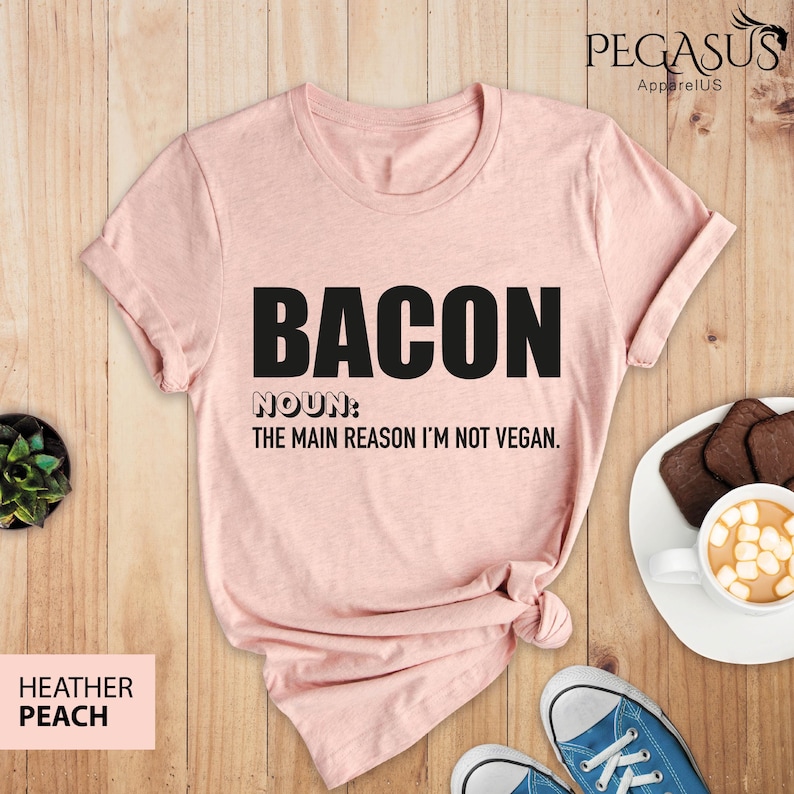 May include: A pink t-shirt with the text "BACON NOUN: THE MAIN REASON I'M NOT VEGAN." printed in black.
