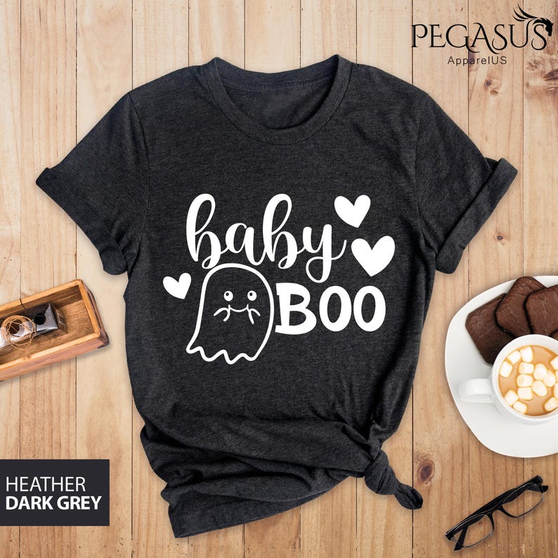 May include: Dark heather grey t-shirt with the words "baby BOO" in white script and a ghost graphic. The shirt also features two white hearts. The text "HEATHER DARK GREY" is in a box in the lower left corner.
