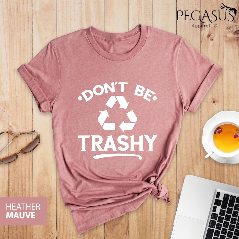 May include: A heather mauve t-shirt with a white graphic that says "Don't Be Trashy" with a recycling symbol.