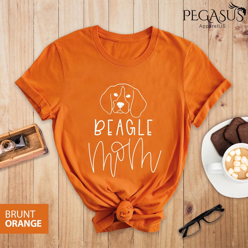 May include: Orange t-shirt with a white outline of a Beagle dog and the text "BEAGLE MOM" in white.