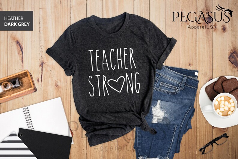 May include: Heather dark grey t-shirt with the text "Teacher Strong" in white with a heart in the middle of the word "Strong".
