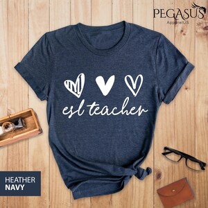 May include: A navy blue t-shirt with the text "esl teacher" and three white hearts. The hearts are drawn in different styles.