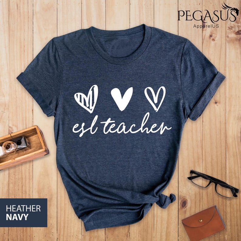 May include: A navy blue t-shirt with the text "esl teacher" and three white hearts. The hearts are drawn in different styles.