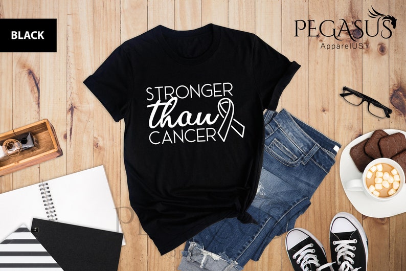 May include: Black t-shirt with white text that reads "Stronger than cancer" and a white ribbon graphic.