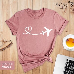 Puede incluir: Camiseta de color malva jaspeado con un avi&oacute;n y un coraz&oacute;n blancos. El gr&aacute;fico muestra un coraz&oacute;n con una l&iacute;nea que se extiende hasta un avi&oacute;n.