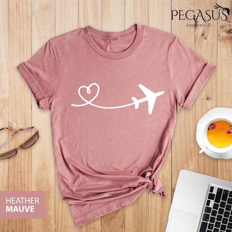 Puede incluir: Camiseta de color malva jaspeado con un avi&oacute;n y un coraz&oacute;n blancos. El gr&aacute;fico muestra un coraz&oacute;n con una l&iacute;nea que se extiende hasta un avi&oacute;n.