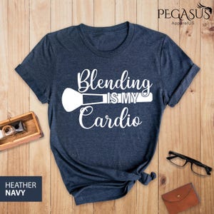 May include: Heather navy blue t-shirt with white text that reads "Blending is my cardio" and a white makeup brush graphic.