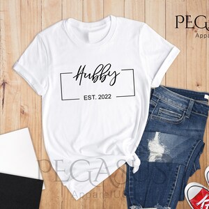 May include: White t-shirt with black text that reads "Hubby Est. 2022" inside a black rectangle.