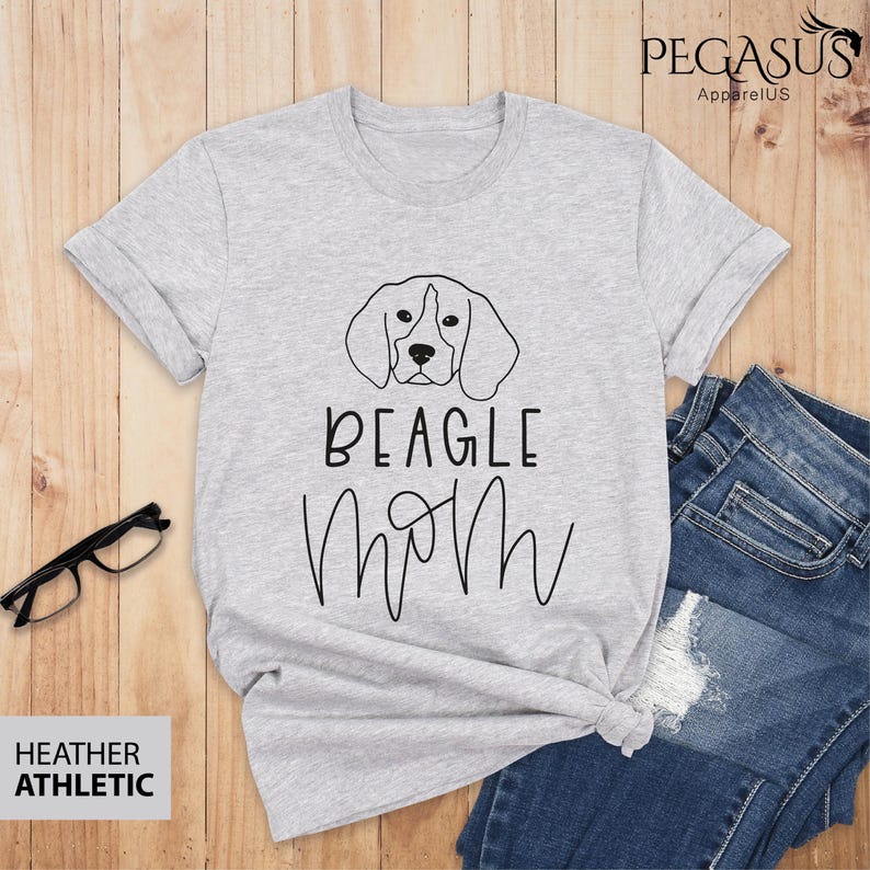 May include: A heather grey t-shirt featuring a black and white illustration of a beagle dog and the text "BEAGLE MOM" in black.
