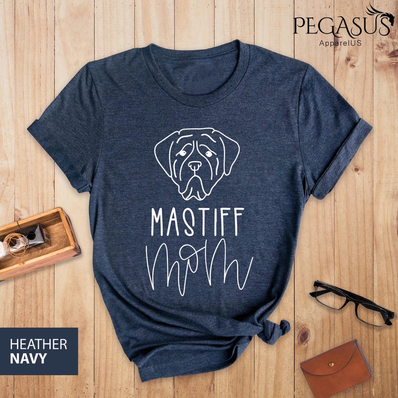 K&ouml;nnte beinhalten: Heather-Marineblaues T-Shirt mit einer wei&szlig;en Umrandung eines Mastiff-Hundekopfes und dem Text "Mastiff Mom" in einer kursivschriftlichen Schrift.