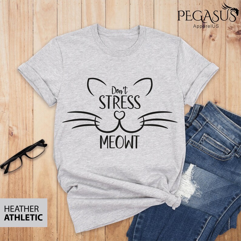 Op de afbeelding: Grijs T-shirt met een zwarte kattenafbeelding en de tekst "Don't Stress Meowt".