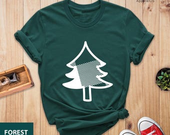 Könnte beinhalten: Ein dunkelgrünes T-Shirt mit einer weißen Silhouette eines karierten Weihnachtsbaums. Der Text "FOREST" befindet sich in der linken unteren Ecke des Bildes. Der Text "PEGASUS ApparelUS" befindet sich in der rechten oberen Ecke des Bildes.