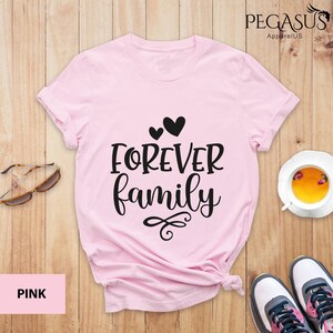 Pode incluir: Camiseta rosa com o texto "FOREVER family" em letras pretas e dois pequenos cora&ccedil;&otilde;es acima do texto.