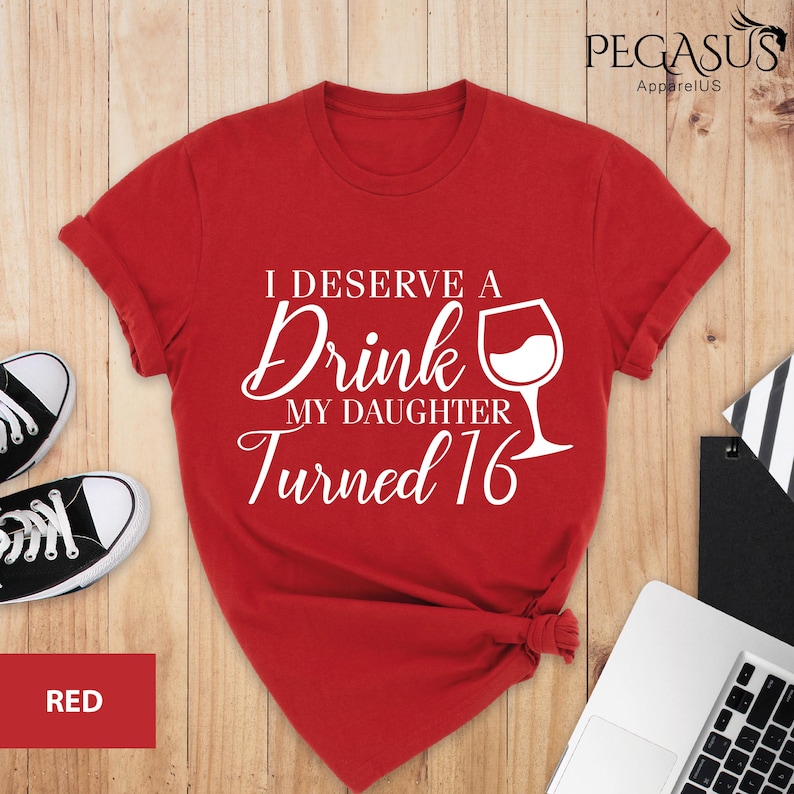 May include: Red t-shirt with white text that reads "I deserve a drink my daughter turned 16" and a white wine glass graphic.
