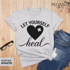 May include: Gray t-shirt with the text "Let yourself heal" and a black heart with a white bandage on it.
