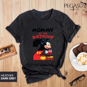 May include: Dark heather grey t-shirt with the text "MOMMY of the BIRTHDAY" in black and red. The number 2 is in black with Mickey Mouse in the center. The word "BOY" is in yellow. The shirt is from Pegasus ApparelUS.