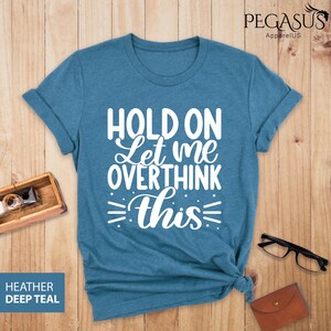 May include: A teal blue t-shirt with the text "Hold on Let me overthink this" in white.