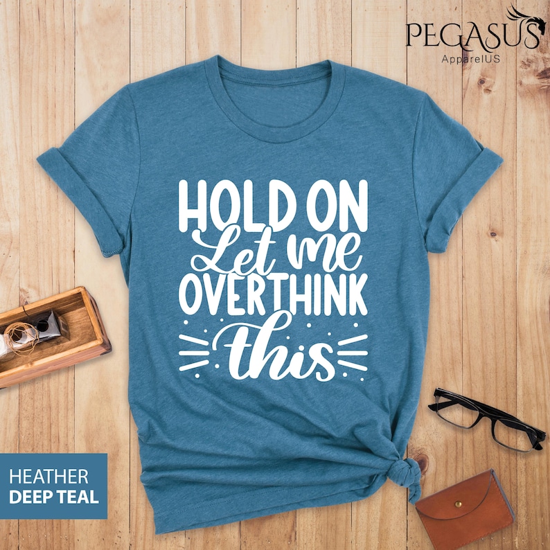 May include: A teal blue t-shirt with the text "Hold on Let me overthink this" in white.